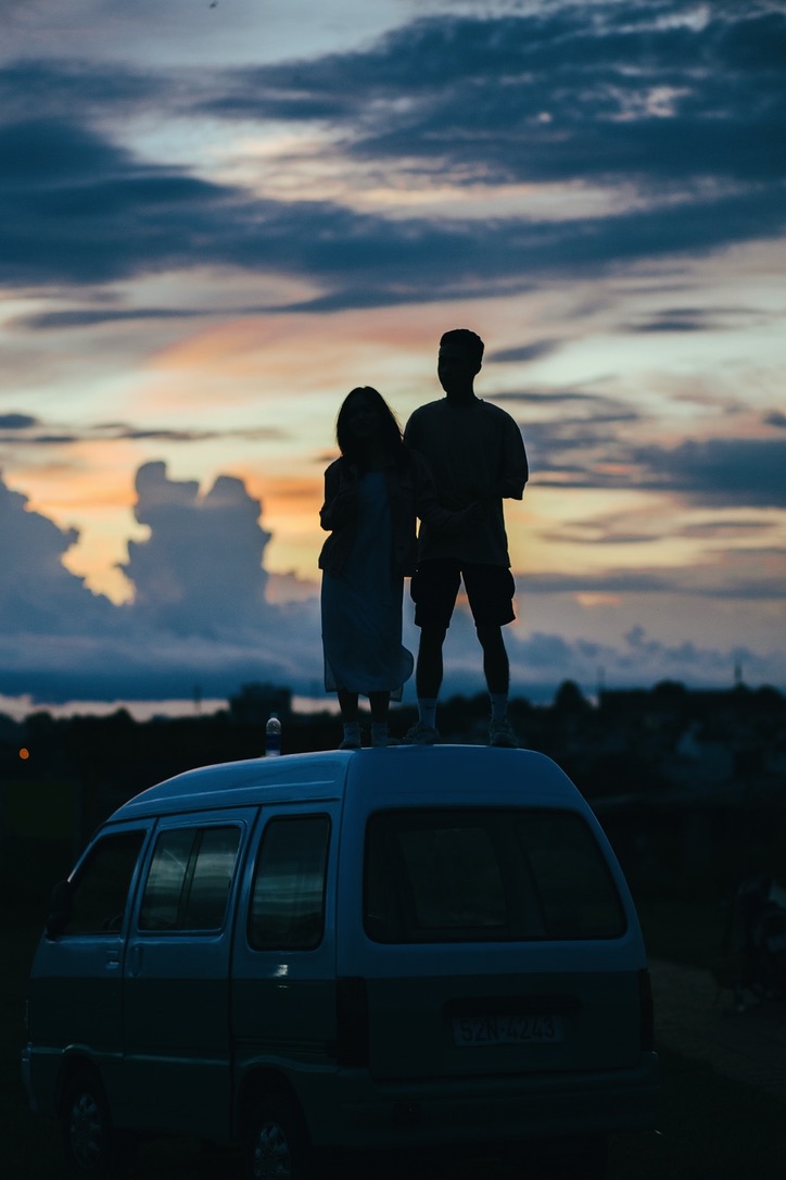 Couple standing in the twilight on their vehicle.